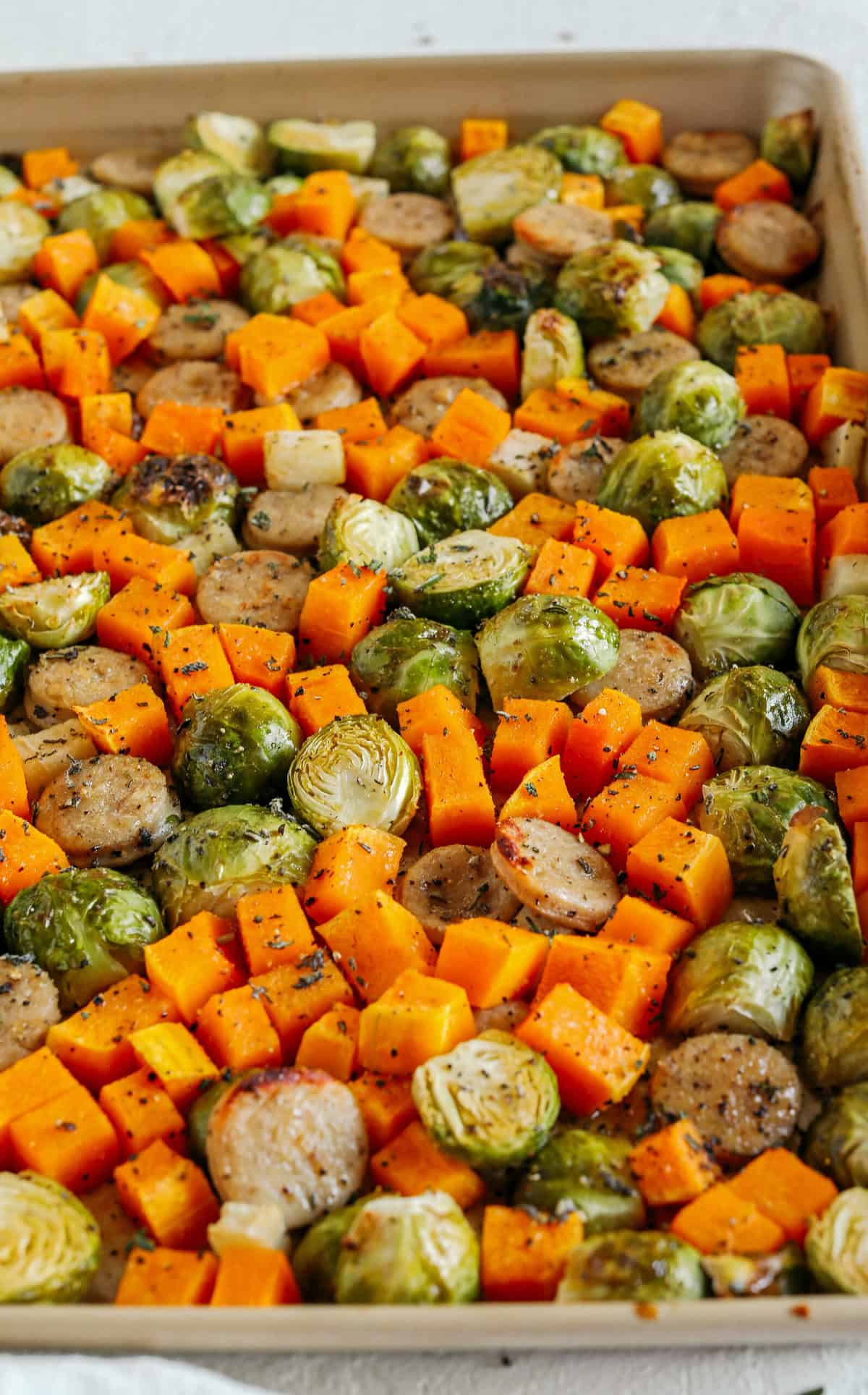Harvest Sheet Pan Sausage and Veggies loaded with flavorful chicken sausage, butternut squash, brussels sprouts, and apples for a quick and easy dinner made in just 30 minutes! Roasted in a maple mustard glaze and fresh herbs for the perfect fall meal!