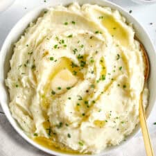 These Healthy Mashed Potatoes are creamy, absolutely delicious and made lighter with Greek yogurt, less potatoes and a whole head of cauliflower! The perfect side dish for your holiday table or weeknight dinner.