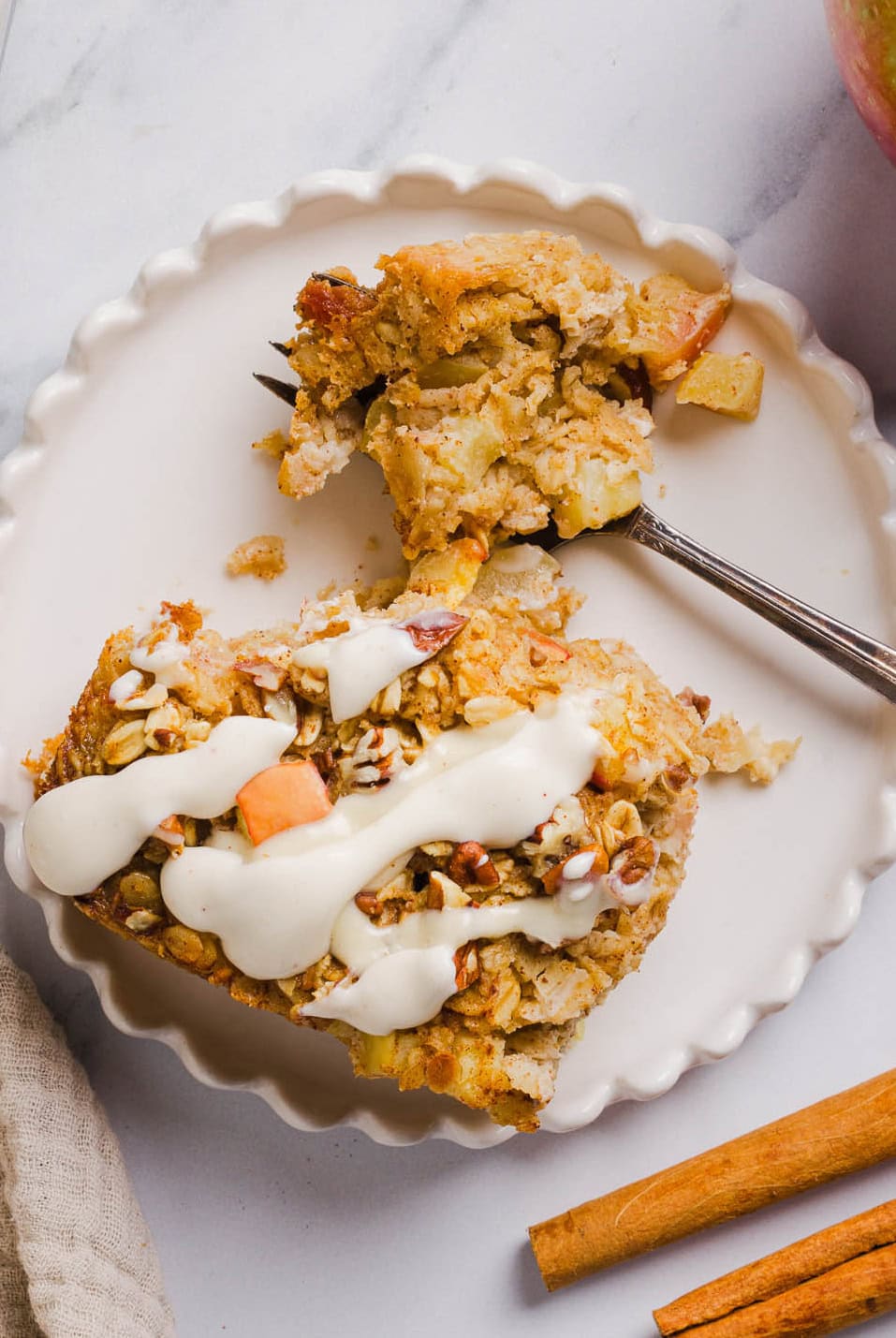 This Apple Cinnamon Baked Oatmeal is a cozy breakfast made with wholesome oats, shredded apples, and warm spices while naturally sweetened with maple syrup and plump raisins! We also topped this with crunchy pecans and a delicious maple cream cheese glaze!
